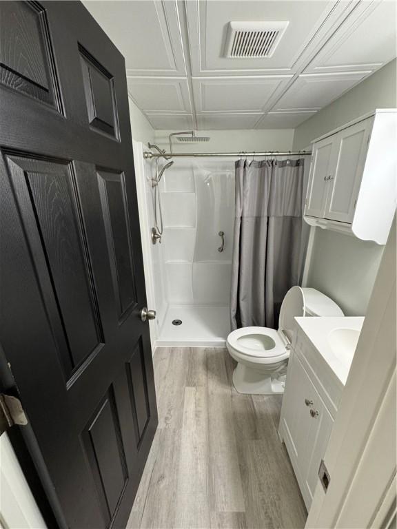 bathroom with toilet, wood finished floors, vanity, visible vents, and a shower with curtain