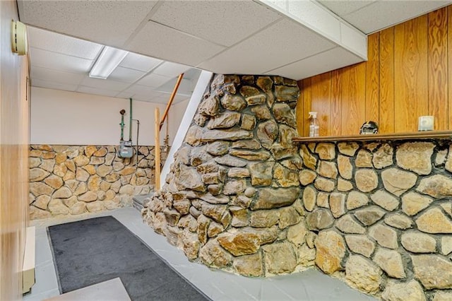 finished below grade area with a wainscoted wall, wooden walls, and a drop ceiling
