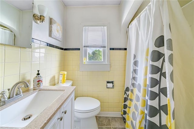 bathroom with tile walls, curtained shower, toilet, vanity, and tile patterned floors