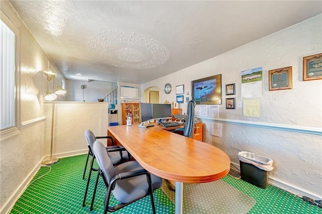 office area with arched walkways, a textured wall, a textured ceiling, and baseboards
