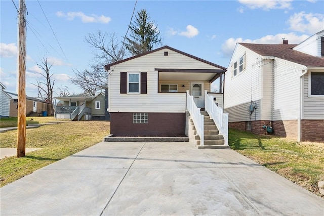 view of front of home with a front yard, covered porch, and stairs