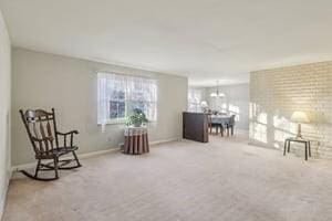 living area featuring a notable chandelier, baseboards, and carpet floors