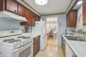 kitchen featuring light countertops, white appliances, under cabinet range hood, a chandelier, and a sink