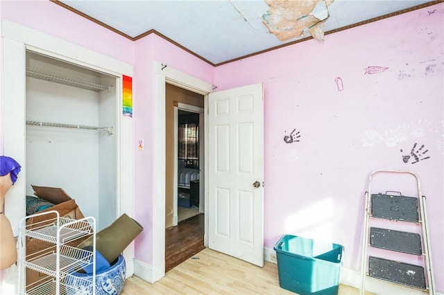 bedroom with light wood-type flooring, a closet, crown molding, and baseboards