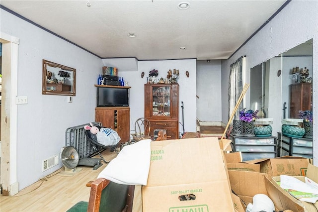 interior space featuring ornamental molding, wood finished floors, and visible vents