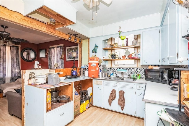 kitchen with light wood-style flooring, ceiling fan, light countertops, open shelves, and a sink