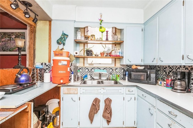 kitchen featuring decorative backsplash, light countertops, black microwave, open shelves, and a sink