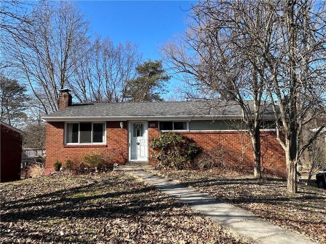 single story home featuring roof with shingles, a chimney, and brick siding