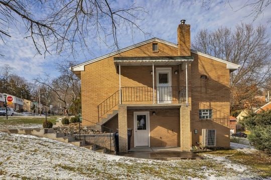 back of house featuring a patio, brick siding, a chimney, and stairway