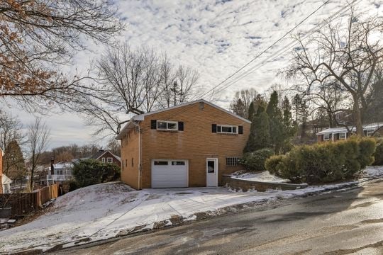 view of snowy exterior with driveway, an attached garage, and fence