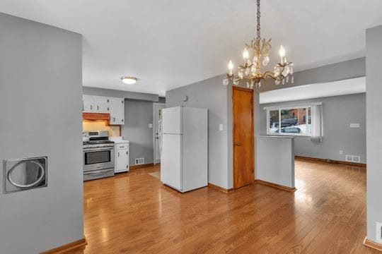 kitchen featuring stainless steel gas stove, light wood-type flooring, freestanding refrigerator, and baseboards