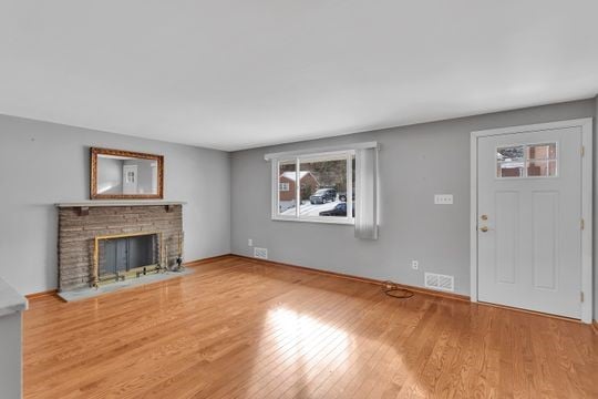 unfurnished living room featuring visible vents, a fireplace, and wood finished floors