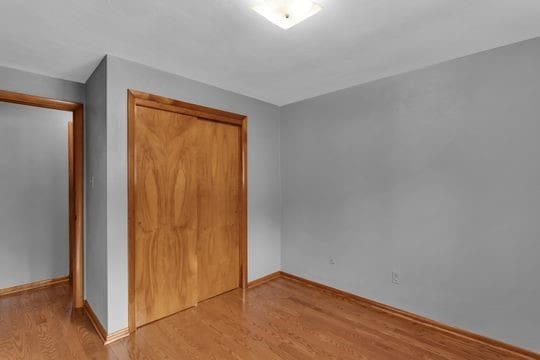 unfurnished bedroom with light wood-style floors, baseboards, and a closet