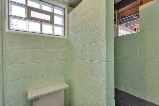 bathroom featuring toilet and concrete block wall