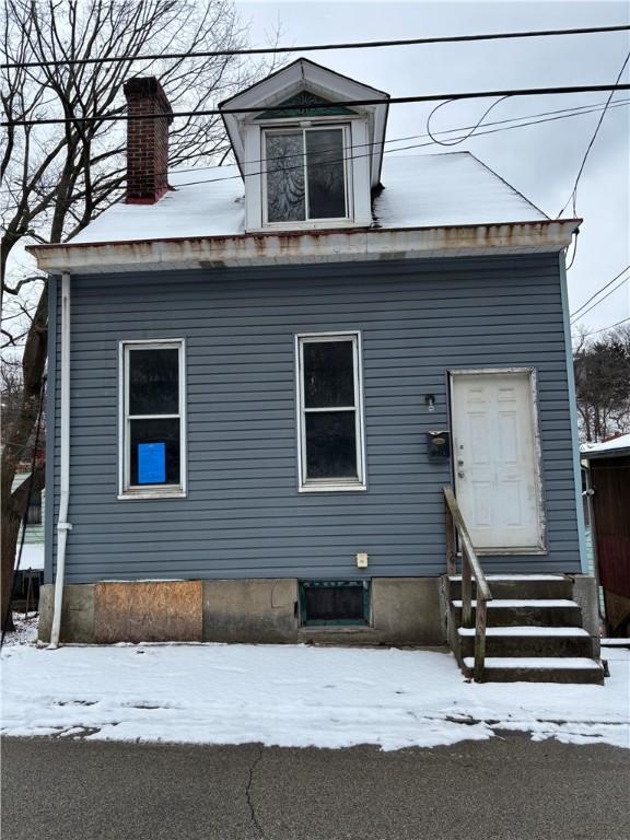 view of front facade with entry steps and a chimney