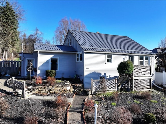 rear view of house featuring fence and metal roof