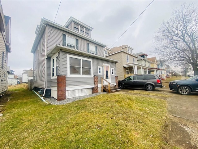 american foursquare style home featuring entry steps, a front yard, and a residential view