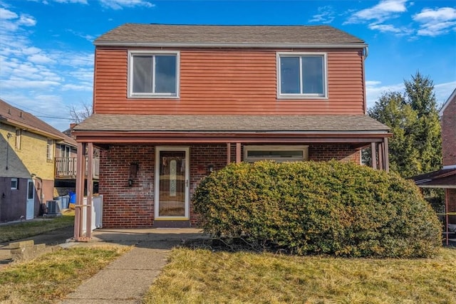 traditional-style home with central AC, brick siding, and a front yard