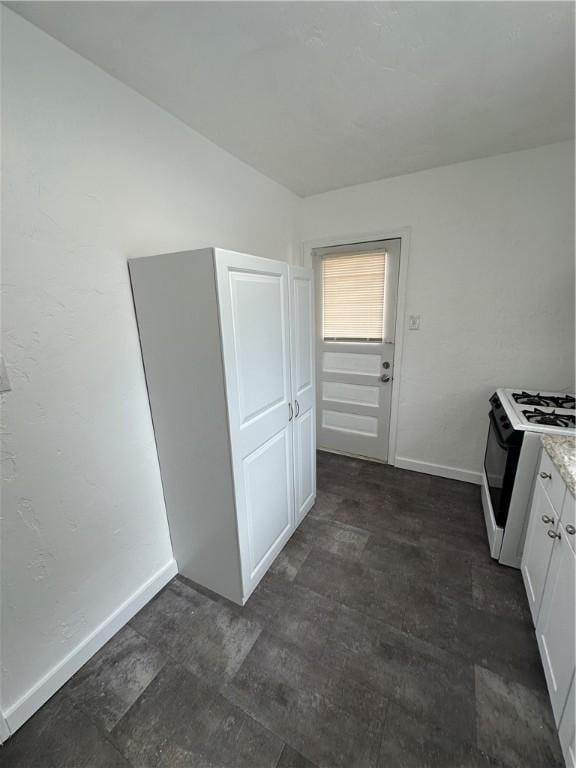 kitchen featuring light countertops, gas stove, white cabinets, and baseboards