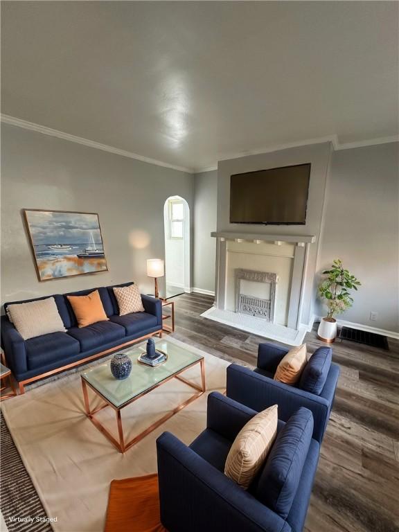 living area featuring baseboards, arched walkways, wood finished floors, and a high end fireplace