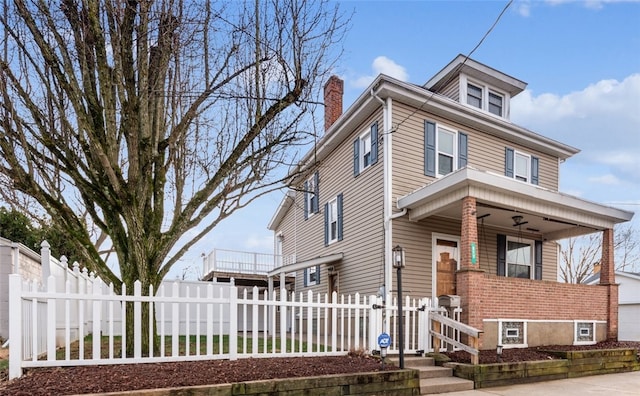 traditional style home featuring brick siding, a fenced front yard, and a chimney