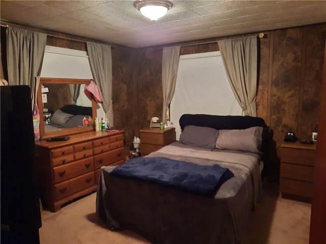 bedroom featuring light colored carpet and wooden walls