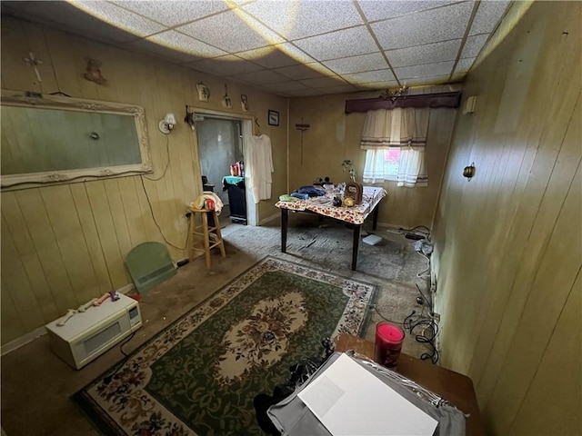 interior space with a paneled ceiling and wood walls