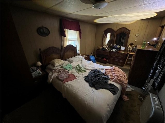 bedroom with wood walls and a paneled ceiling