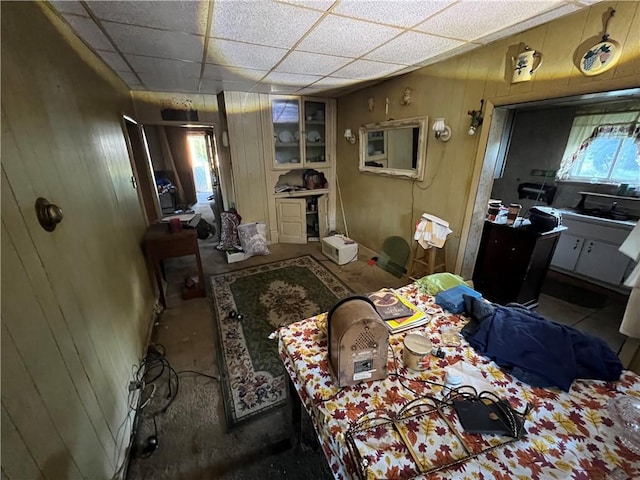 bedroom featuring wooden walls and a drop ceiling