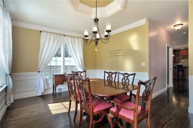 dining space featuring dark wood-style floors, ornamental molding, and a wainscoted wall