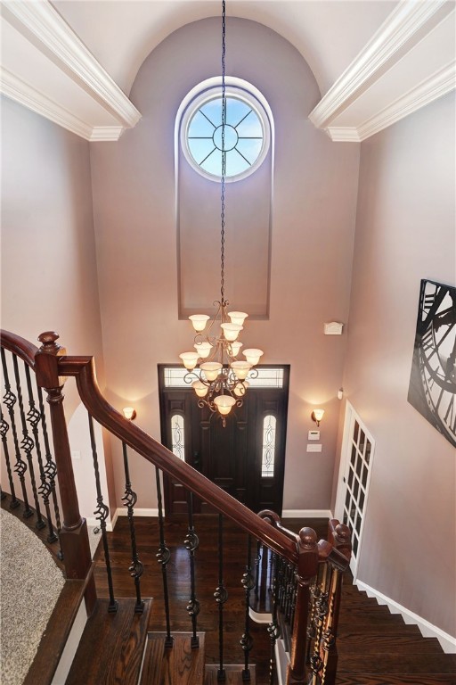 staircase featuring ornamental molding, vaulted ceiling, wood finished floors, a chandelier, and baseboards