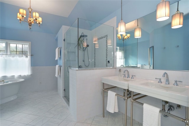 bathroom with a notable chandelier, tile walls, a freestanding bath, wainscoting, and a shower stall