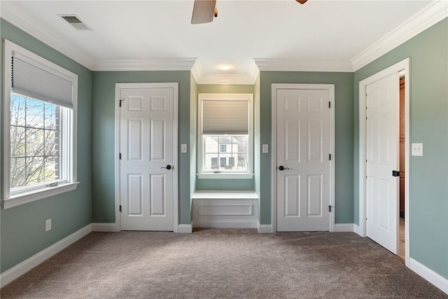 unfurnished bedroom featuring ceiling fan, carpet floors, visible vents, baseboards, and crown molding