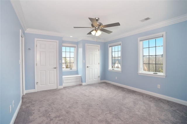 unfurnished bedroom with carpet floors, visible vents, ornamental molding, and baseboards