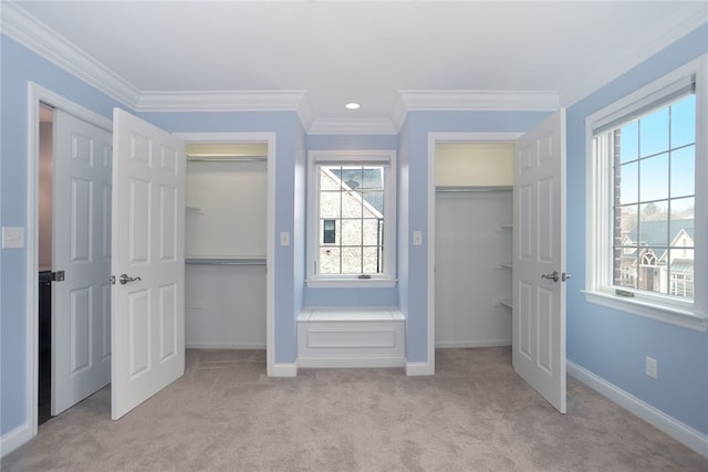 unfurnished bedroom featuring crown molding, carpet flooring, two closets, and baseboards