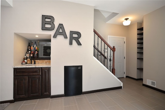 bar with a dry bar, visible vents, stairway, a sink, and baseboards