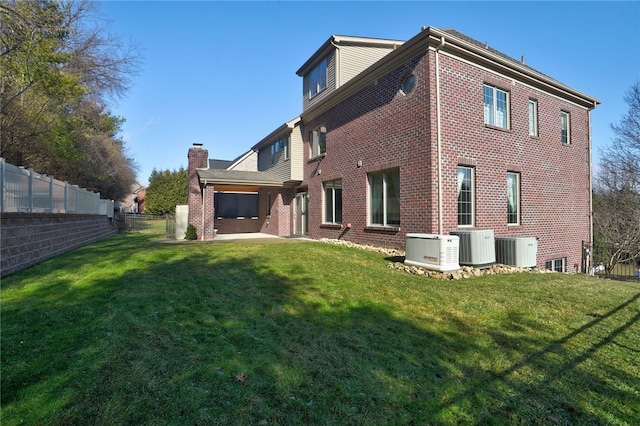 back of property with a patio, a fenced backyard, central air condition unit, brick siding, and a yard