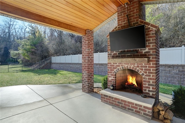 view of patio / terrace with an outdoor brick fireplace and a fenced backyard