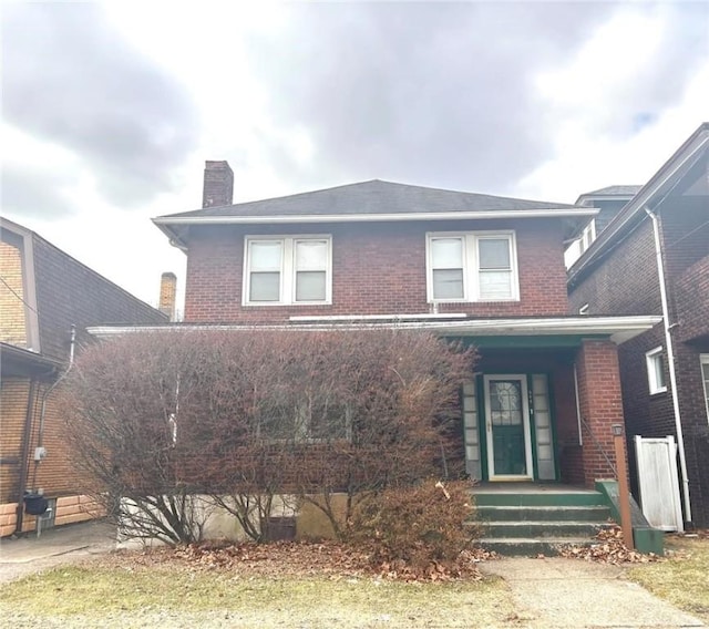 american foursquare style home featuring brick siding and a chimney