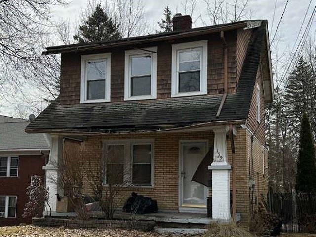 view of front of home with brick siding and a chimney