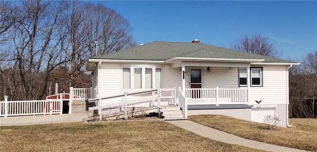 view of front of home featuring covered porch, roof with shingles, and a front yard