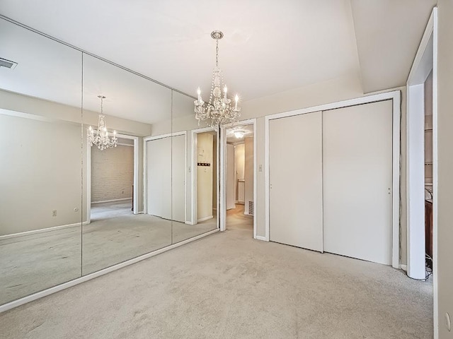 unfurnished bedroom with carpet floors, a closet, visible vents, and a notable chandelier