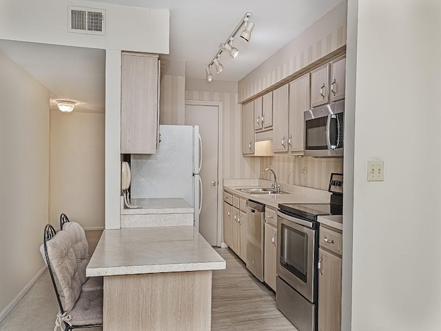 kitchen with visible vents, a breakfast bar, stainless steel appliances, light countertops, and a sink