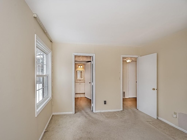 unfurnished bedroom featuring light carpet and baseboards