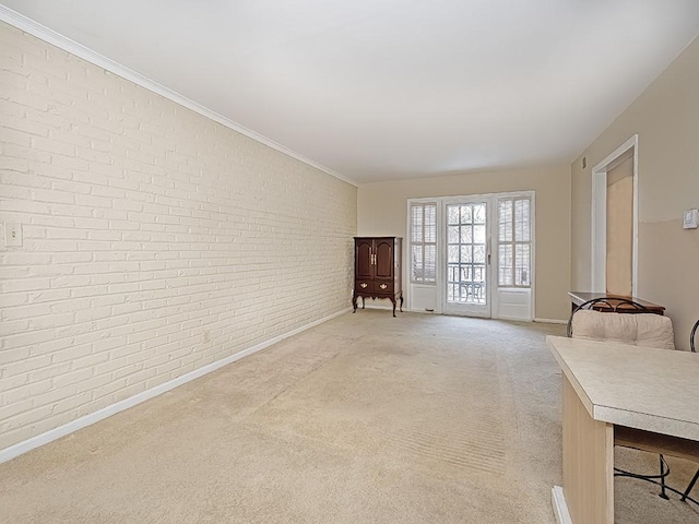 unfurnished living room with light carpet, brick wall, crown molding, and baseboards