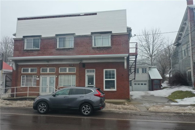 view of front facade featuring a garage, french doors, brick siding, and an outdoor structure