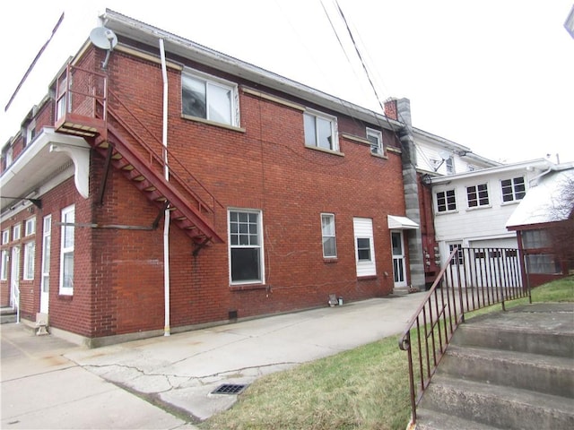 view of home's exterior featuring brick siding, a chimney, and stairs