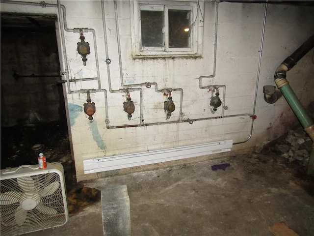 basement featuring a baseboard heating unit and concrete block wall