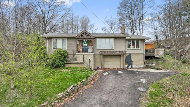 view of front of property featuring a garage, brick siding, a chimney, and aphalt driveway