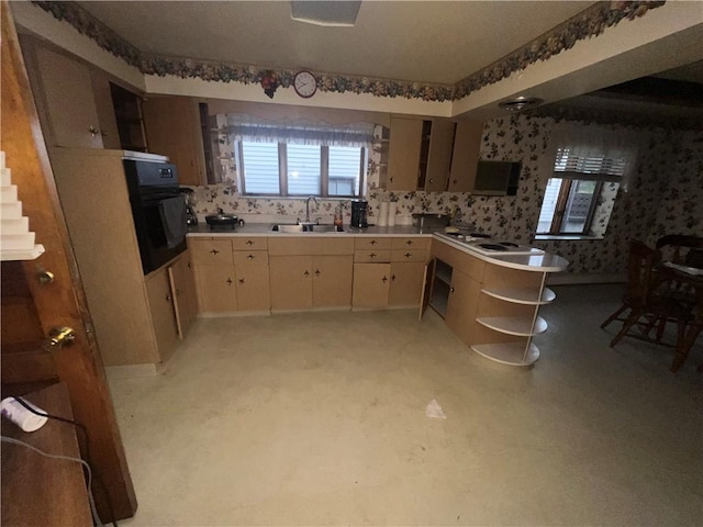 kitchen featuring cooktop, light countertops, a sink, oven, and wallpapered walls